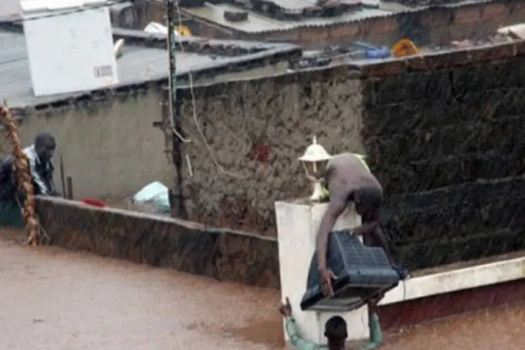 
	Morador de Maputo entrega um aparelho de televis&atilde;o durante uma enchente: a situa&ccedil;&atilde;o n&atilde;o p&ocirc;de ser avaliada em alguns povoados isolados
 (Stringer/AFP)