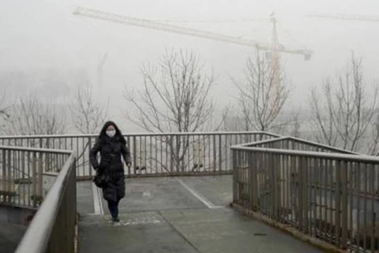 
	Chinesa passa por uma ponte usando uma m&aacute;scara: pedestres passeavam apesar das advert&ecirc;ncias das autoridades para que permanecessem em casa
 (Wang Zhao/AFP)