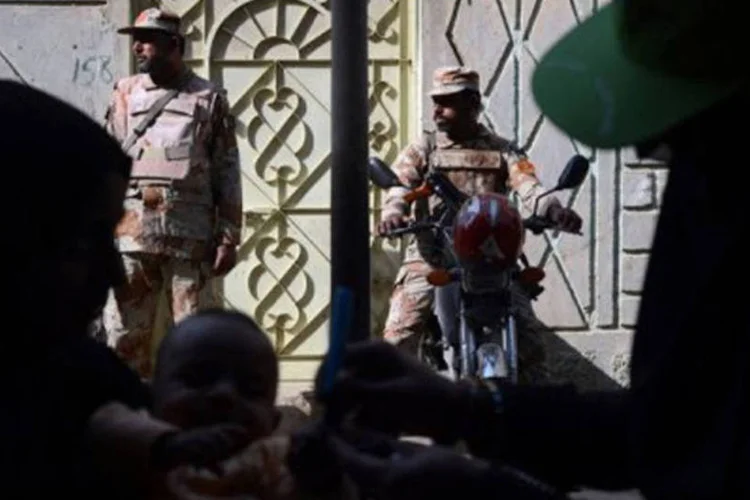 
	Soldados paquistaneses em alerta enquanto um trabalhador vacina uma crian&ccedil;a contra p&oacute;lio em Karachi: talib&atilde;s suspeitam que a campanha &eacute; um disfarce para espionagem
 (Asif Hassan/AFP)