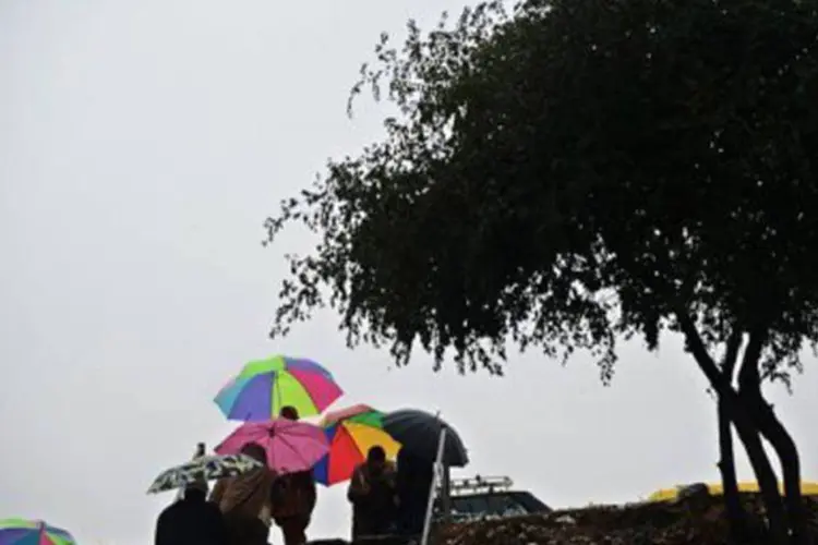 
	Pessoas se protegem da chuva em Islamabad: tr&ecirc;s soldados foram dados como desaparecidos depois de um deslizamento&nbsp;
 (Farooq Naeem/AFP)