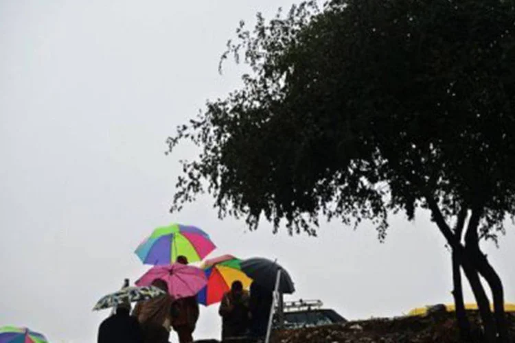 
	Pessoas se protegem da chuva em Islamabad: tr&ecirc;s soldados foram dados como desaparecidos depois de um deslizamento&nbsp;
 (Farooq Naeem/AFP)