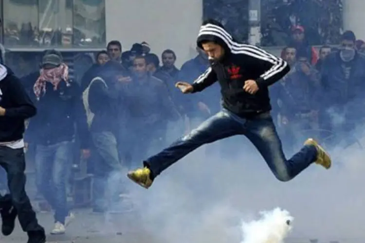 
	Tunisiense pula sobre uma bomba de g&aacute;s durante protesto em T&uacute;nis: dist&uacute;rbios deixaram um morto entre os policiais
 (Fethi Belaid/AFP)