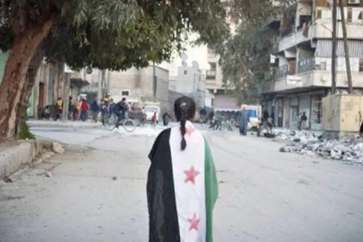 
	Menina s&iacute;ria com a antiga bandeira nacional em Alepo: os criminosos moram em localidades xiitas, enquanto os ref&eacute;ns s&atilde;o de regi&otilde;es sunitas (Bruno Gallardo/AFP)