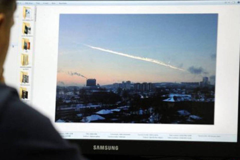 
	Homem olha uma foto do meteorito: n&atilde;o est&aacute; claro se este meteorito est&aacute; vinculado ao aster&oacute;ide 2012 DA 14, que deve passar a 27.000 km da Terra ainda nesta sexta-feira
 (Yuri Kadobnov/AFP)
