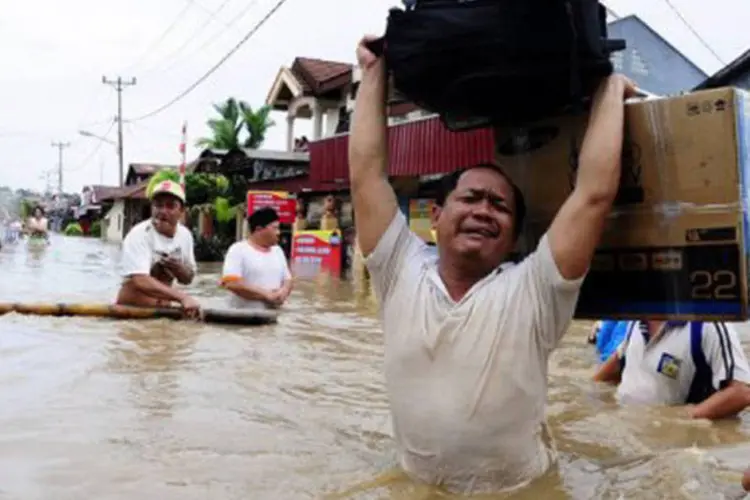 
	Moradores salvam seus pertences enquanto enchente assolam a cidade de Manado, na Indon&eacute;sia: cerca de 8.100 pessoas tiveram que ser realojadas
 (Yudi Makka/AFP)