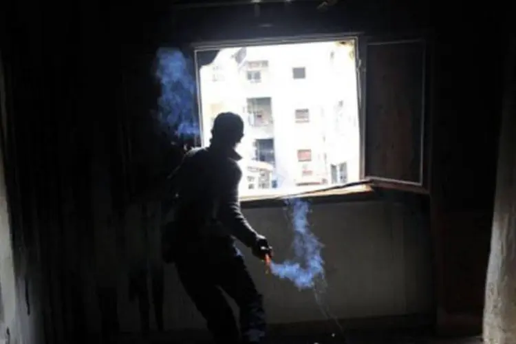 Rebelde lança uma granada contra forças do governo sírio, em Alepo
 (Bulent Kilic/AFP)