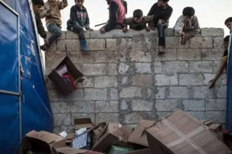 
	Crian&ccedil;as refugiadas recolhem caixas vazias, em um campo localizado na fronteira com a Turquia: estes quatro milh&otilde;es representam quase um em cada cinco s&iacute;rios
 (Edouard Elias/AFP)