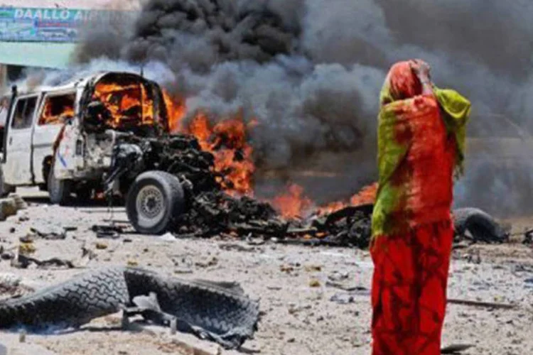 
	Mulher somali observa carro-bomba ainda em chamas ap&oacute;s atentado em Mogad&iacute;scio: entre os mortos, est&atilde;o quatro funcion&aacute;rios estrangeiros, quatro guardas de seguran&ccedil;a e sete milicianos
 (Mohamed Abdiwahab/AFP)