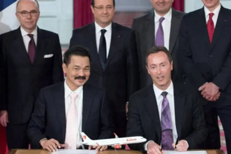 
	Hollande cercado por Rusdi Kirana (E), presidente da Lion Air, e o CEO da Airbus, Fabrice Bregier (D): para enfatizar a magnitude do acontecimento, o contrato foi assinado no Pal&aacute;cio do Eliseu
 (Bertrand Langlois/AFP)