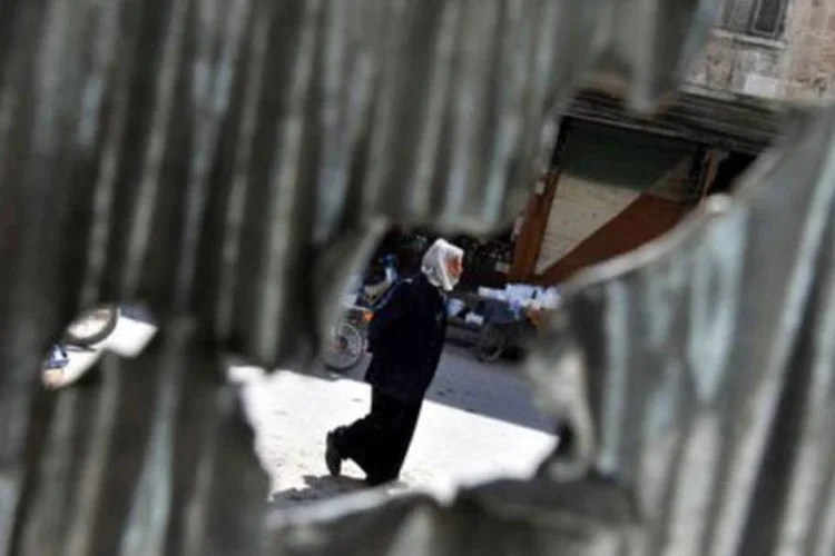 
	S&iacute;rio fotografado atrav&eacute;s de buraco em barreira de metal na cidade de Maarat al-Numan: o governo s&iacute;rio pediu ontem a Ban Ki-moon que abra uma investiga&ccedil;&atilde;o oficial
 (Bulent Kilic/AFP)