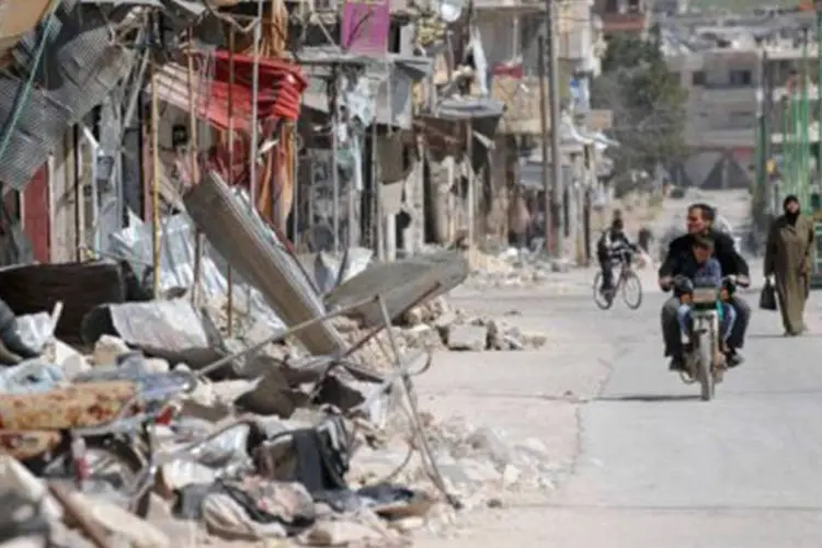 
	S&iacute;rios caminham em meio a constru&ccedil;&otilde;es destru&iacute;das em Maarat al-Numan, na prov&iacute;ncia de Idleb: segundo a ONU, mais de 70.000 pessoas morreram em dois anos de conflito
 (Bulent Kilic/AFP)