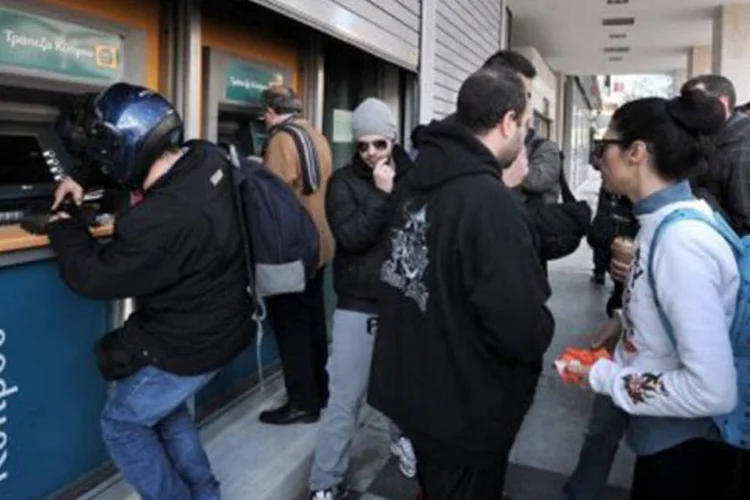 
	Clientes retiram dinheiro em massa de caixas eletr&ocirc;nicos do Cyprus Bank: as filiais portuguesas ser&atilde;o recapitalizadas pelos bancos gregos, por sua vez resgatados pela Europa
 (Louisa Gouliamaki/AFP)
