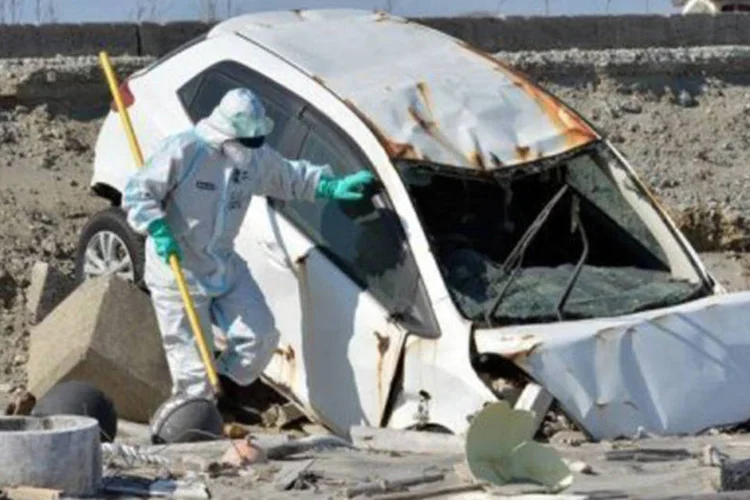 
	Policial com roupa protetora observa ve&iacute;culo destru&iacute;do em Namie:&nbsp;&nbsp;na cidade que chegou a ter 21.000 habitantes, n&atilde;o resta uma alma
 (Yoshikazu Tsuno/AFP)