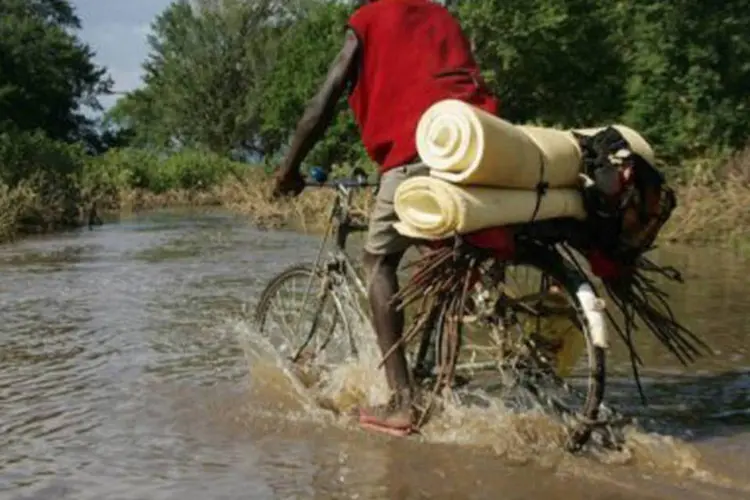 
	Ciclista caminha em meio a regi&atilde;o alagada de Arusha, na Tanz&acirc;nia, em 2008: as paredes desabaram ap&oacute;s fortes chuvas
 (Simon Maina/AFP)