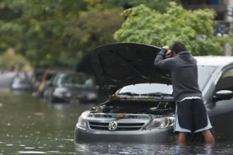 
	Um homem revisa seu carro em uma via alagada em Buenos Aires: v&aacute;rias pessoas ficaram presas em seus carros ou em lugares p&uacute;blicos durante toda a noite em fun&ccedil;&atilde;o da chuva
 (José Luis Perrino/AFP)