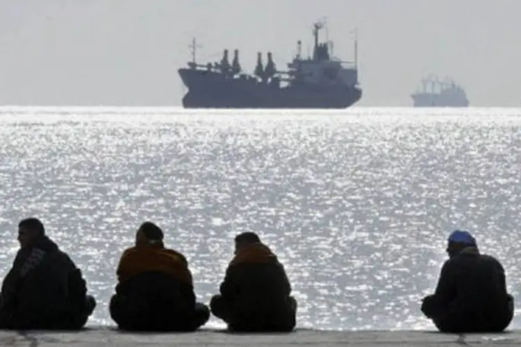 
	Pessoas sentadas em p&iacute;er observam embarca&ccedil;&otilde;es em Safaga, no Egito: os tripulantes do navio foram presos
 (Cris Bouroncle/AFP)