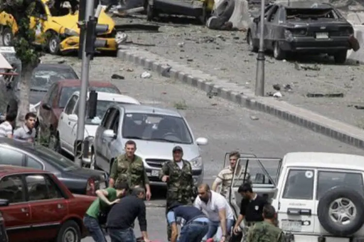 
	Feridos s&atilde;o retirados de local de atentado em Damasco: a explos&atilde;o aconteceu em uma &aacute;rea residencial, perto de uma escola que tamb&eacute;m foi atingida
 (Louai Beshara/AFP)