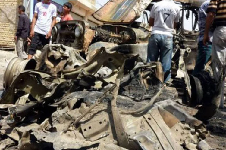 
	Estudantes observam os restos de ve&iacute;culos destru&iacute;dos, no leste de Bagd&aacute;: quase 20 carros-bomba explodiram em todo o pa&iacute;s
 (Ali al-Saadi/AFP)