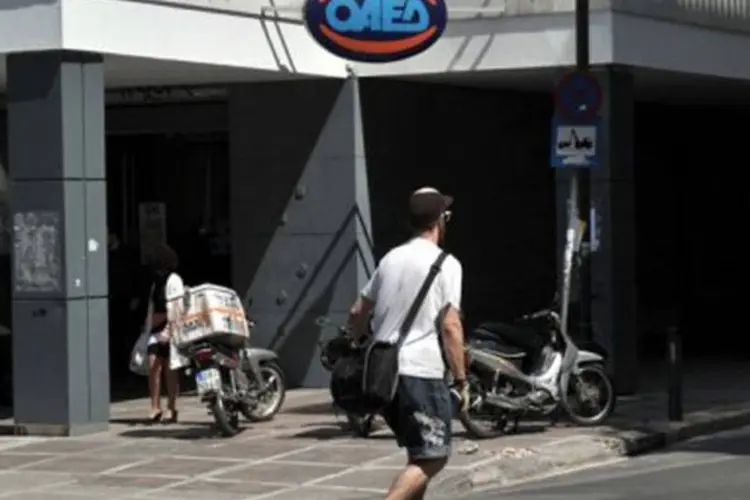 
	Homem passa de skate por loja fechada na Gr&eacute;cia: nesse pa&iacute;s, 66% dos trabalhadores querem trabalhar mais
 (Louisa Gouliamaki/AFP)