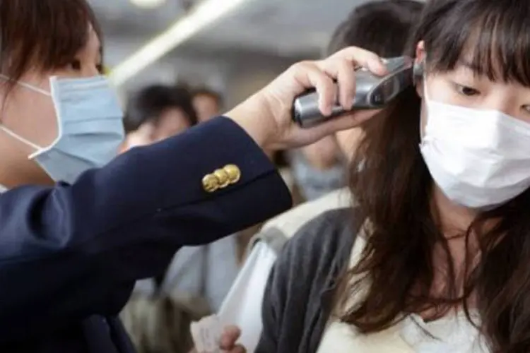 
	Passageira tem sua temperatura conferida no aeroporto Sungshan de Taipei: o homem infectado apresentou sintomas de gripe tr&ecirc;s dias depois do retorno a Taip&eacute;, via Xangai
 (Sam Yeh/AFP)