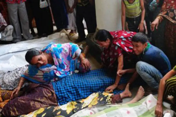 
	Parentes choram junto ao corpo de uma das v&iacute;timas: segundo servi&ccedil;o de emerg&ecirc;ncia, ainda existem pessoas sepultadas sob os escombros que pedem ajuda
 (Munir Uz Zaman/AFP)