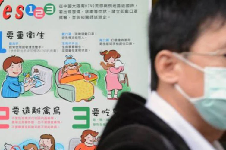 
	Homem se protege com m&aacute;scara e cartaz d&aacute; orienta&ccedil;&otilde;es sobre a gripe: foram registradas 120 infec&ccedil;&otilde;es humanas
 (Sam Yeh/AFP)