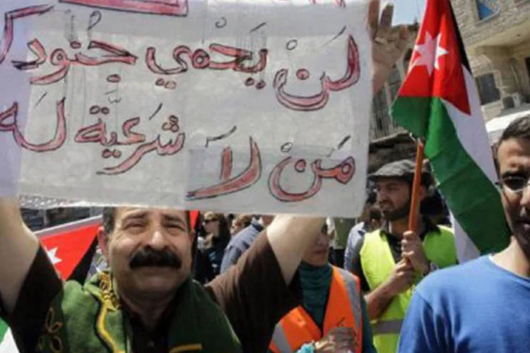 
	Jordaniano segura cartaz em protesto contra os EUA: quase 400 pessoas marcharam pela Cidade Velha de Am&atilde; cantando &quot;N&oacute;s n&atilde;o queremos ver (soldados) americanos&quot;
 (Khalil Mazraawi/AFP)