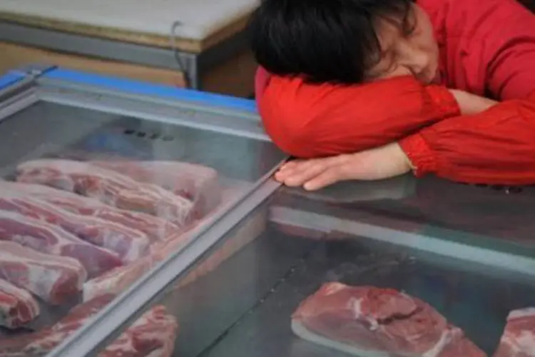 
	Vendedora de carne de porco cochila em um mercado de Xangai: entre os casos, havia ainda carne estragada e produtos que continham carne t&oacute;xica e perigosa
 (Peter Parks/AFP)