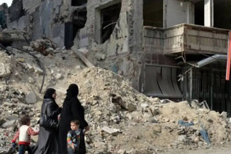 Mulheres e crianças caminham diante de hospital destruído em Alepo, norte da Síria
 (Miguel Medina/AFP)
