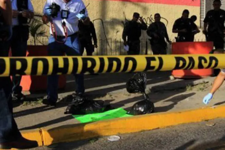 
	Policiais recolhem provas no local de crime em Guadalajara: os funcion&aacute;rios do bar teriam o agredido quando descobriram que ele n&atilde;o poderia pagar a conta
 (Héctor Guerrero/AFP)