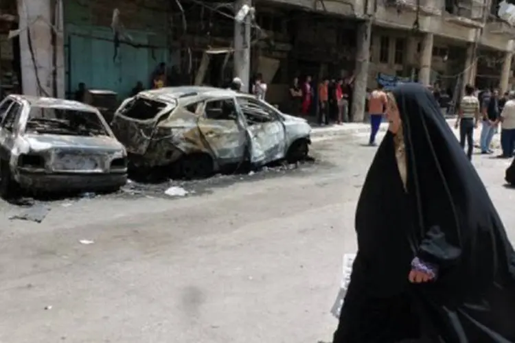 
	Mulher passa ao lado de carros incendiados em Bagd&aacute;: entre as v&iacute;timas, est&atilde;o cinco membros de uma fam&iacute;lia sunita
 (Sabah Arar/AFP)