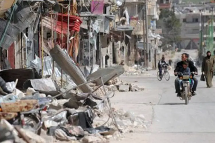 Sírios se deslocam por área destruída de Maarat al-Numan, na província de Idlib, em 20 de março
 (Bulent Kilic/AFP)