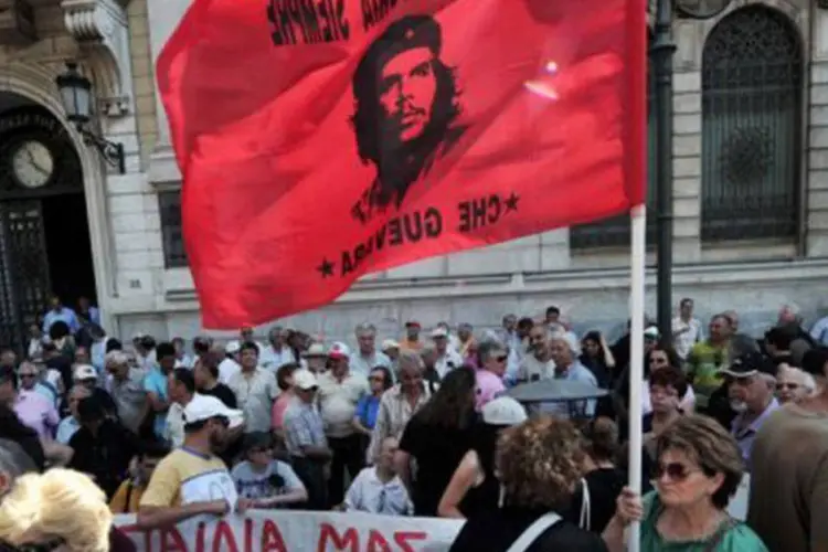 Uma manifestante segura uma bandeira com a imagem de Che Guevara (Louisa Gouliamaki/AFP)