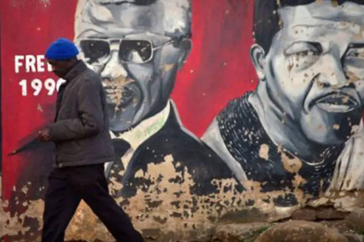 Um homem caminha em frente a um muro pintado com o rosto do ex-presidente sul-africano Nelson Mandela
 (Mujahid Safodien/AFP)