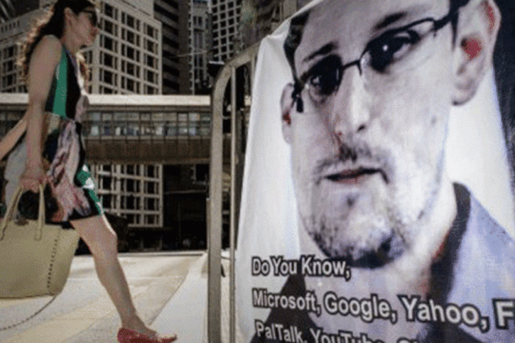 
	Uma mulher caminha ao lado de um banner de apoio a Edward Snowden: a&ccedil;&atilde;o acusa os m&eacute;todos de espionagem norte-americanos revelados pelo ex-funcion&aacute;rio da intelig&ecirc;ncia
 (Philippe Lopez/AFP)