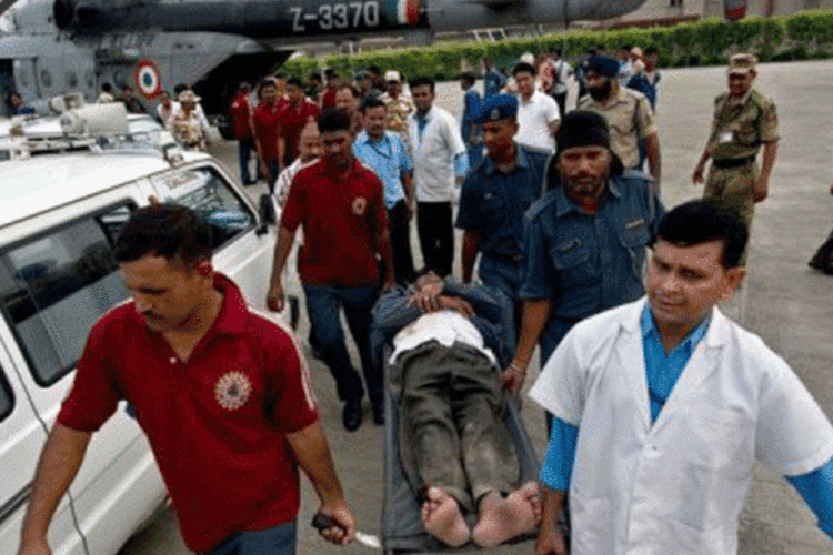 Um peregrino indiano, retirado do local das enchentes, é transportado por médicos em uma maca: milhares de soldados foram enviados à região para socorrer pessoas em áreas remotas (.)