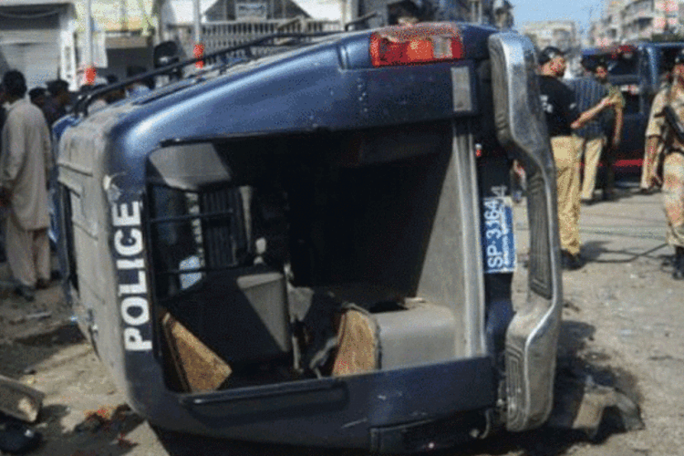 Seguranças em torno de um carro de polícia destruído pelo ataque em Karachi: ataque também deixou 14 feridos (Rizwan Tabassum/AFP)