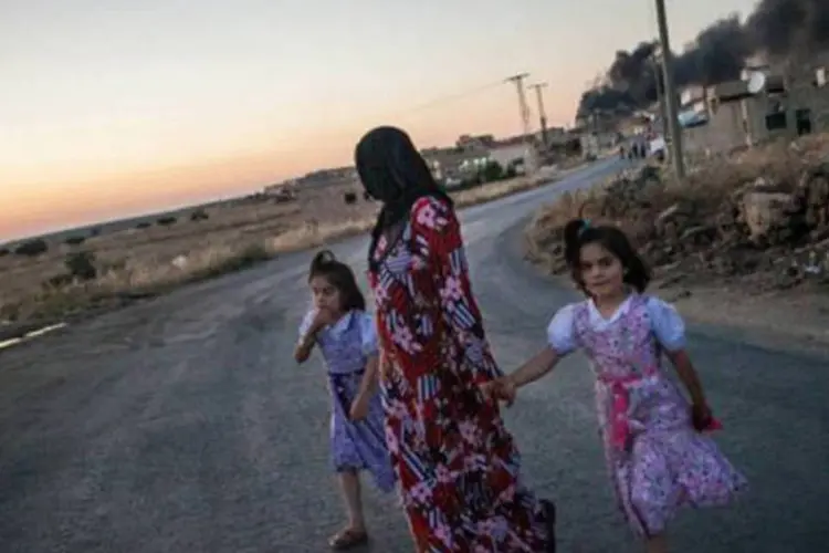 Família deixa para trás uma coluna de fumaça, em Al Bara, Síria: Conselho "convida a comunidade internacional a enviar a assistência necessária o quanto antes" para ajudar os refugiados do país (Daniel Leal Olivas/AFP)