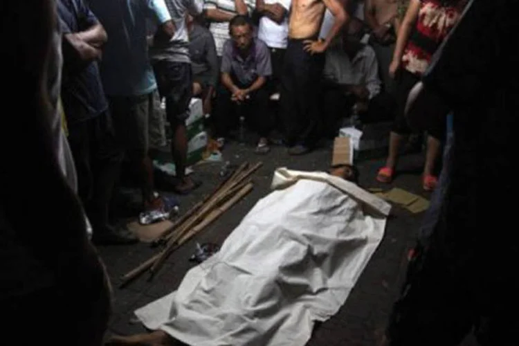 Chineses ao redor do corpo do vendedor de melancias: agentes de regulação locais espancaram chinês até a morte por vender melancias em uma barraca de rua sem licença (AFP)