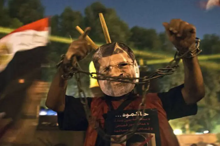 
	Homem usa m&aacute;scara de Mursi: partid&aacute;rios do l&iacute;der islamista deposto fizeram manifesta&ccedil;&otilde;es contr&aacute;rias para exigir sua restaura&ccedil;&atilde;o como presidente, ignorando a amea&ccedil;a de uma repress&atilde;o iminente
 (Khaled Desouki/AFP)