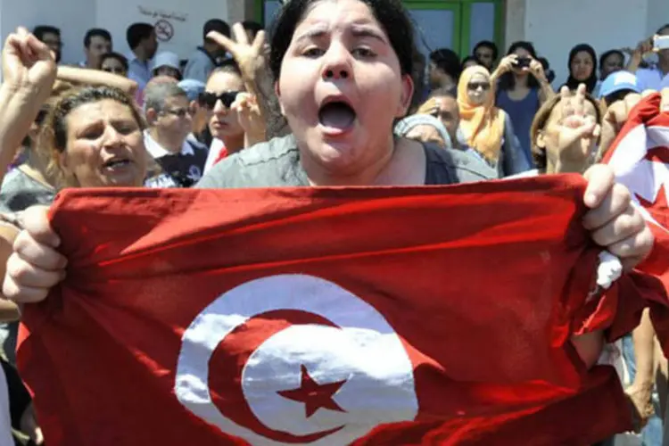 Filha do político opositor Mohamed Brahmi, em protesto em Ariana com a bandeira da Tunísia (Fethi Belaid/AFP)