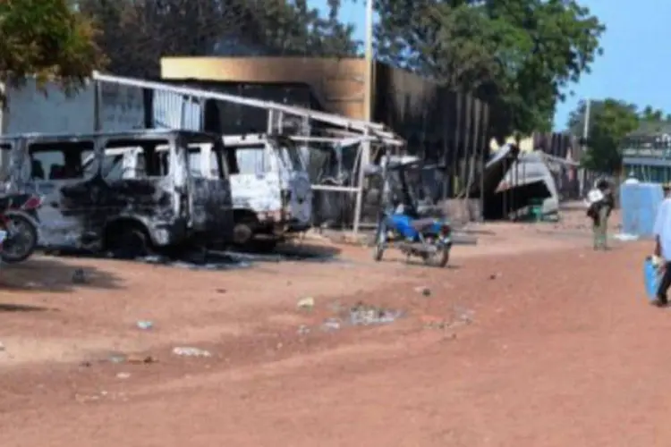 
	Pessoas passam por ve&iacute;culos e lojas queimados pelos islamitas do Boko Haram, numa rua de Benisheik, na Nig&eacute;ria
 (AFP)