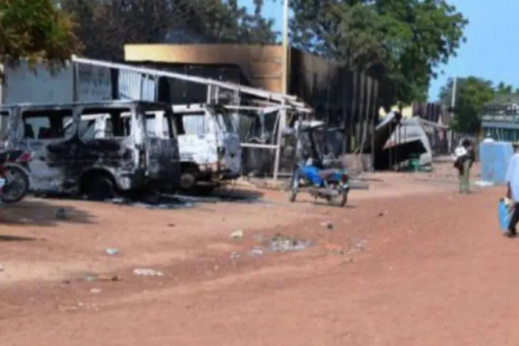 Pessoas passam por veículos e lojas queimados pelos islamitas do Boko Haram, numa rua de Benisheik, na Nigéria
 (AFP)