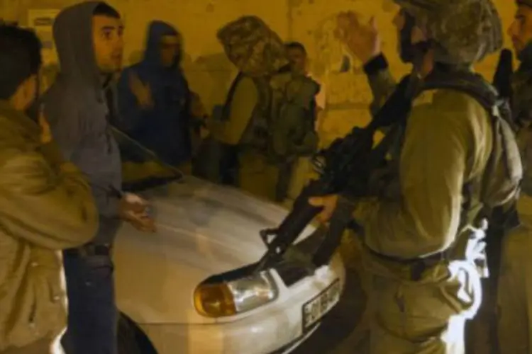 
	Soldados israelenses conversam com palestinos: um soldado israelense morreu no domingo ap&oacute;s ser baleado por um suposto atirador palestino na cidade de Hebron
 (Ahmad Gharabli/AFP)