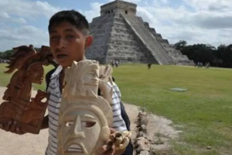 Menino vende artefatos maias próximo a uma pirâmide no sítio de Chichen Itza, em Yucatan (Cris Bouroncle/AFP/maia, arqueologia)