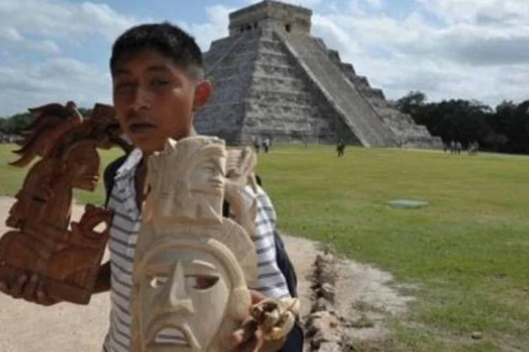 Menino vende artefatos maias próximo a uma pirâmide no sítio de Chichen Itza, em Yucatan (Cris Bouroncle/AFP/maia, arqueologia)