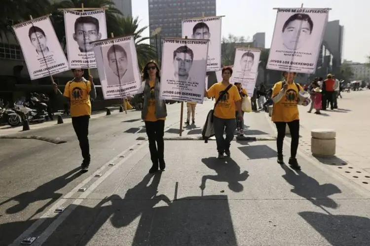 
	Pessoas seguram placas com imagens de alguns dos 43 estudantes desaparecidos desde setembro
 (Reuters/Henry Romero)