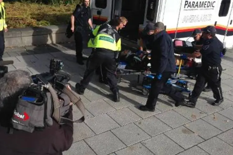 Polícia e equipes médicas removem uma pessoa ferida no parlamento do Canadá, cenário de vários disparos (Michel Comte/AFP)
