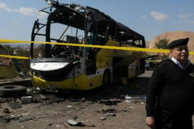 Policial egípcio protege os destroços do ônibus que foi alvo de atentado no domingo no Sinai: ação foi um ato suicida (Nameer Galal/AFP)