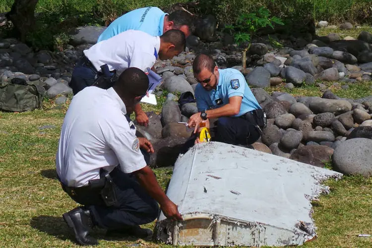 Polícia francesa inspeciona o pedaço de avião encontrado na praia de Saint-Andre (Reuters/ Prisca Bigot)